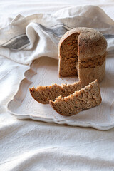 Dinkelbrot in German that means spelt wholemeal bread. The wheat alternative. Dinkel or Spelt is an ancient grain grown organically in Europe. Off white textile background with linen towel.
