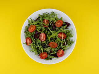healthy tomato and mix leaves salad on yellow background