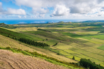 Fototapeta na wymiar Green fields of ranch pasture on Terceira island in the famous Serra do Cume with Atlantic Ocean on the horizon, Azores PORTUGAL