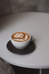 Flat white coffee, flower latte art on white table, hipster coffee shop concept. Minimalist background, copy space