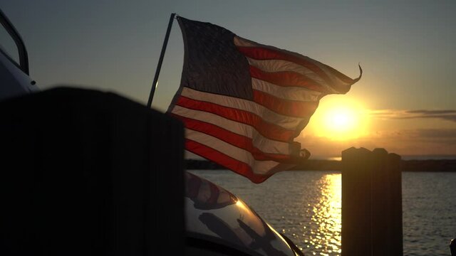american flag flying in the wind at sunset