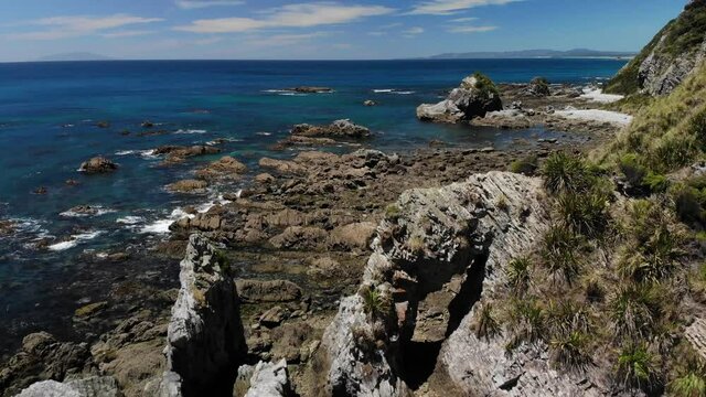 Drone fly over tunnel rock formation at New Zealand coast. Summer day at Mangawhai Heads