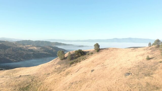 Photographer, Hiker Sitting Atop Impressively Large Climbing Boulder Near Santa Barbara, California. Zoom In and Past Drone Shot, Double Reveal.