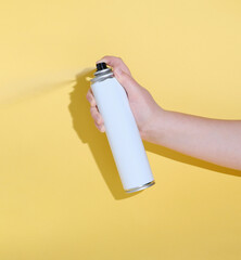 hand holding a tin can and spraying a product over a yellow background. mock up for product design....