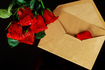 Envelope and bouquet of red roses on black table. Valentines day.