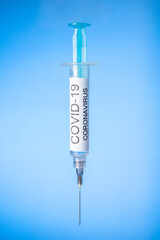 Covid-19 coronavirus syringe vaccine on blue background. copy space