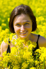 a happy girl smiles in a yellow rapeseed field