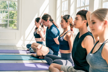 Multi ethnic group of Asian, Caucasian male and female work out yoga together in studio room with natural light. Concept of diversity, healthy lifestyle with copy space.