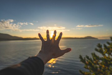 朝陽に手を伸ばす男性