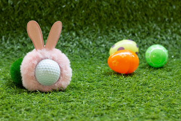 Naklejka premium Golf Easter with rabbit hat on golf ball with Easter eggs behind on green grass