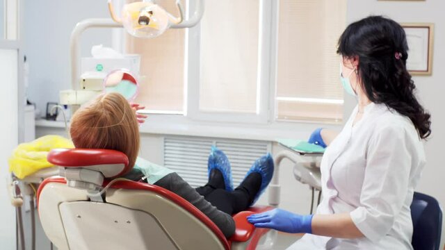 Dentist is giving the patient a mirror and checking her teeth with dental mirror. Dental clinic