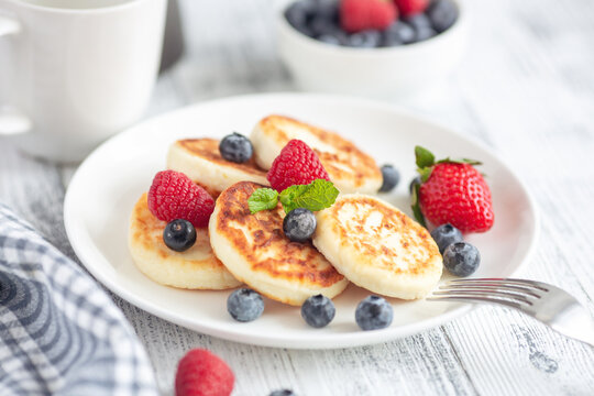 Cottage cheese pancakes with fresh berries on white wooden table. Breakfast or lunch. Syrniki - Image
