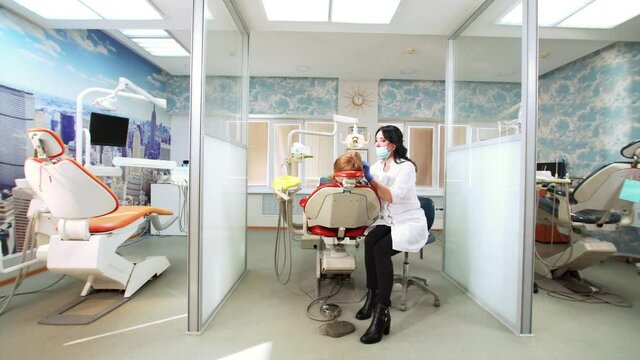 Dental cabinet devided into 3 sections. In the middle dentist works with patient