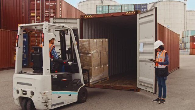 Forklift Driver Loading a Shipping Cargo Container with a Full Pallet with Boxes in Logistics Port Terminal