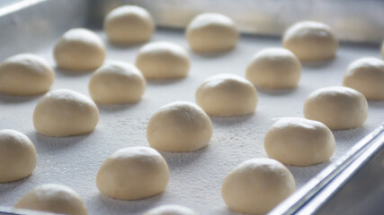 Fototapeta na wymiar close up of doughnut dough balls in baking sheet with white flour