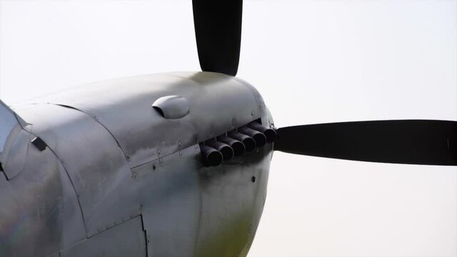 Spitfire fighter plane engine start up tight shot showing exhausts puffing oil smoke and prop starting to spin up.