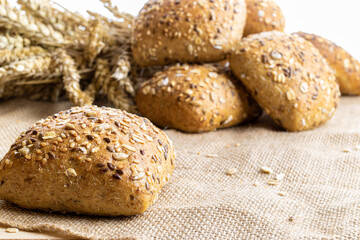 Home baked bread. Rye bakery with crusty loaves and crumbs. Fresh rustic traditional bread with wheat grain ear or spike plant on natural cotton background. Design element for bakery product label.