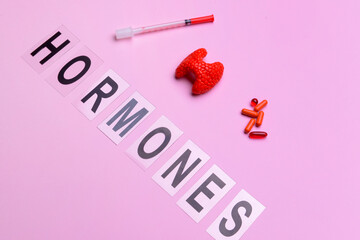 Word HORMONES, thyroid gland, pills and syringe on color background