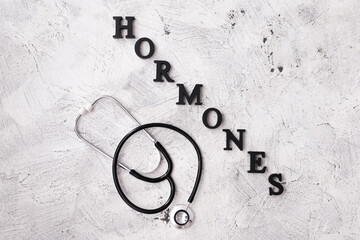 Word HORMONES and stethoscope on grey background