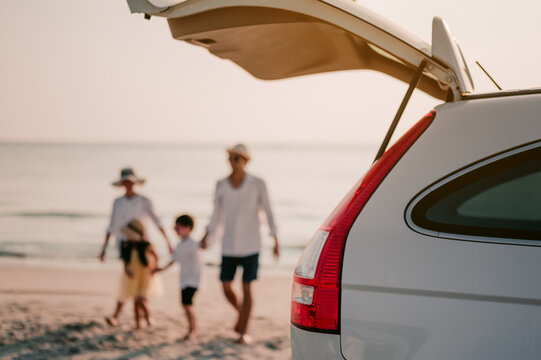 Asian Family Vacation Holiday, Happy Family Walking On The Beach In The Sunset.Happy Family Is Walking Into The Car.Back View Of A Happy Family On A Tropical Beach And A Car On The Side.