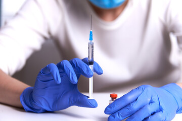 a woman holds an injection syringe in front of her. Vaccination in a pandemic