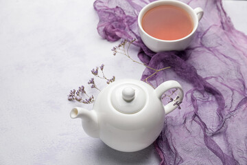 Teapot and cup of tea on light background