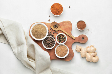 Board with different spices on white background