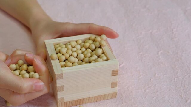 枡に入った大豆を掬う女性の手