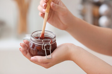 Woman with jar of delicious homemade plum jam at home