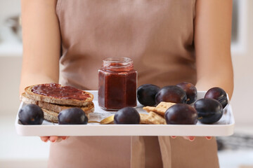Woman holding tray with delicious homemade plum jam