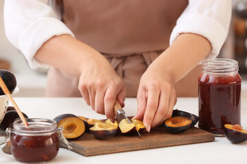 Obraz na płótnie Canvas Woman cutting plums for preparing delicious jam