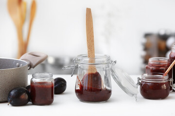 Glass jars with delicious homemade plum jam on table