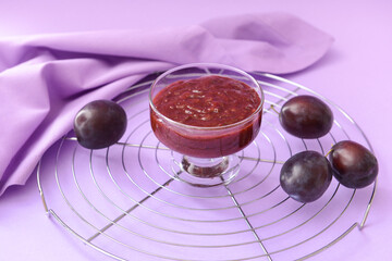 Bowl with delicious homemade plum jam on color background