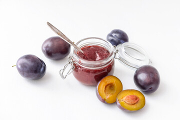 Glass jar with delicious homemade plum jam on white background