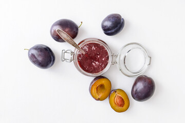 Glass jar with delicious homemade plum jam on white background