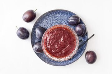 Bowl with delicious homemade plum jam on white background
