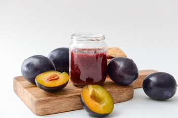 Glass jar with delicious homemade plum jam on white background