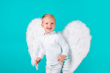 Beautiful little angel isolated. Valentines day. Cute child boy in white dress standing over blue...