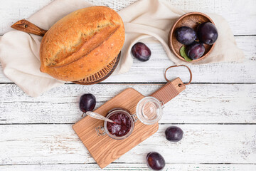 Glass jar with delicious homemade plum jam on wooden background