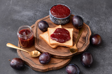 Composition with delicious homemade plum jam on dark background
