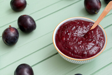 Bowl with delicious homemade plum jam on wooden background