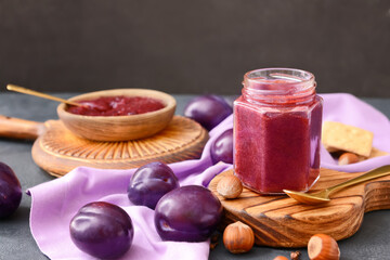 Composition with delicious homemade plum jam on dark background