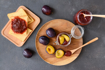 Composition with delicious homemade plum jam on dark background