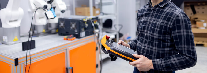 Engineer operator controls automatic mechanical robot arm to weld and collect car parts