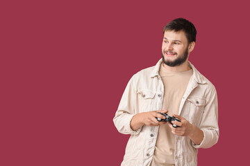Fototapeta na wymiar Young man playing video games against color background