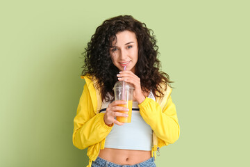 Portrait of stylish young woman with cup of juice on color background