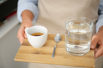 Young barista with hot espresso in cafe, closeup