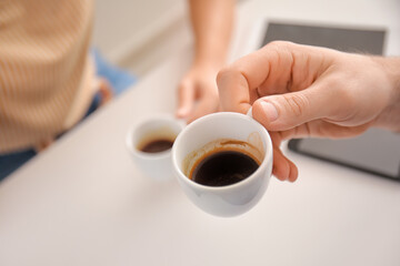 Man with cup of hot espresso in cafe, closeup