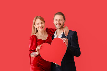 Fototapeta na wymiar Young couple with red heart on color background. Valentine's Day celebration