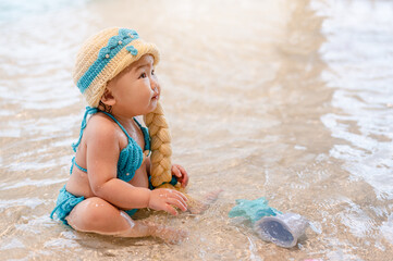 Little girl is wearing swimsuit and wear a cute hairpiece.Having fun in swimming pool,Summer and vacation,Asian Family concept. and wear a cute golden hairpiece.in swimming pool, Family concept.